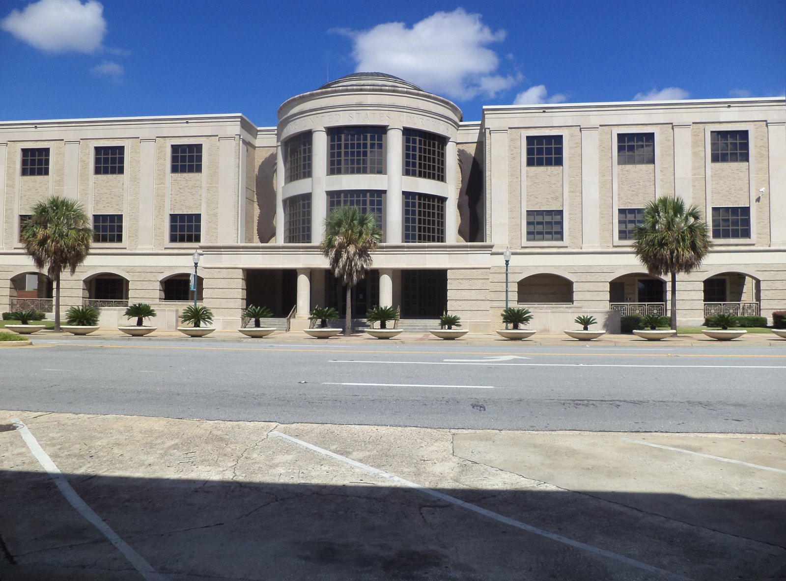 The federal courthouse in Albany, Georgia, a pale stone building with a rounded, columned center and palm trees in front