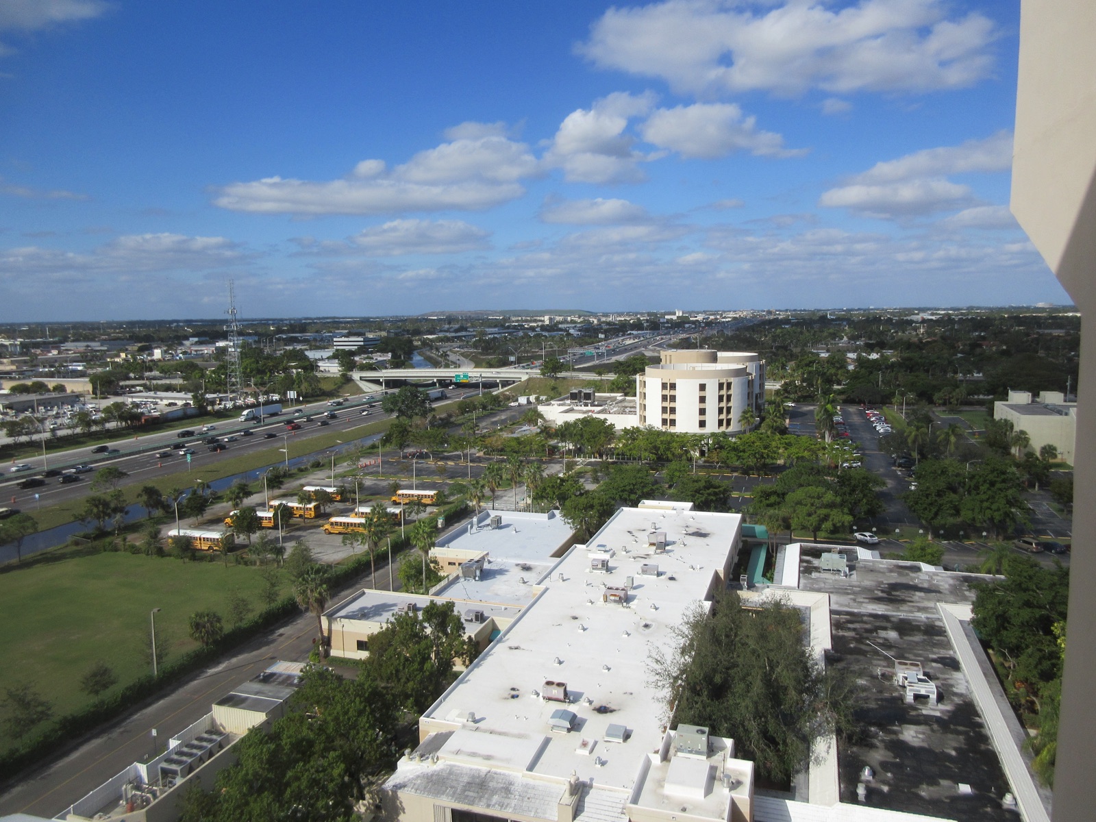 An aerial view of Pompano Beach, Florida, with low buildings, trees and a highway under a blue sky