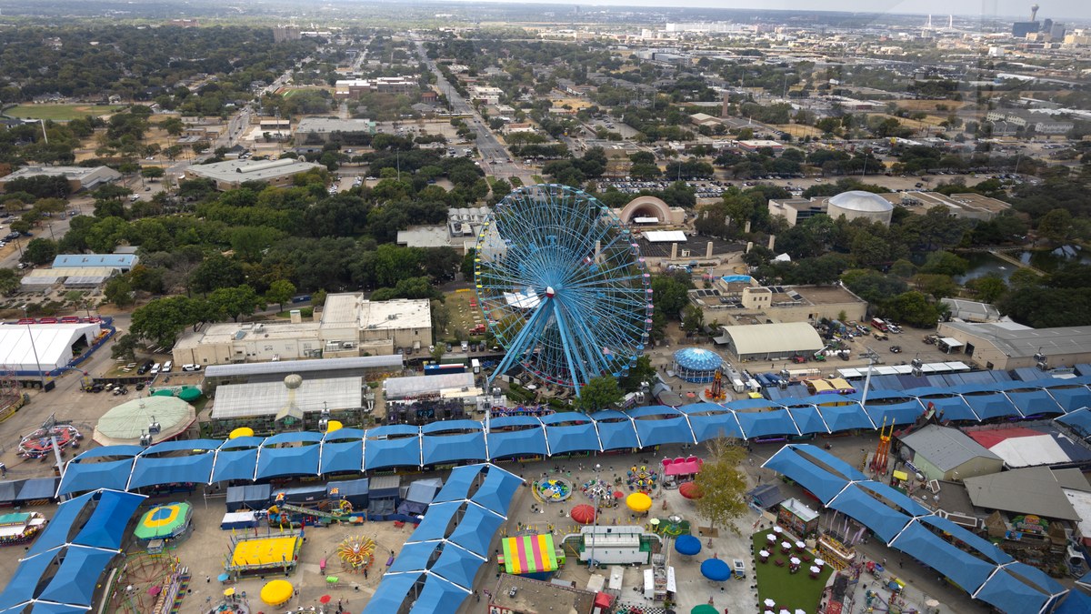 An aerial view of the State Fair of Texas Midway at Fair Park with the Texas Star Ferris wheel and blue booth canopies